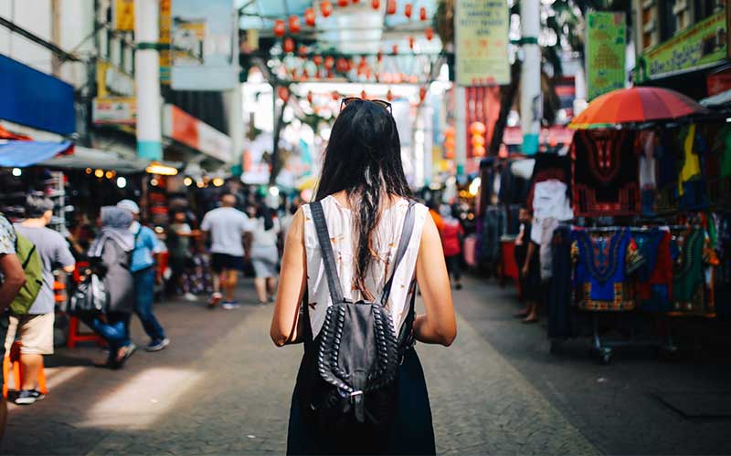 Young female traveller walking through the stalls in Chinatown