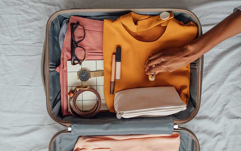 Open suitcase with clothes, glasses and makeup case within